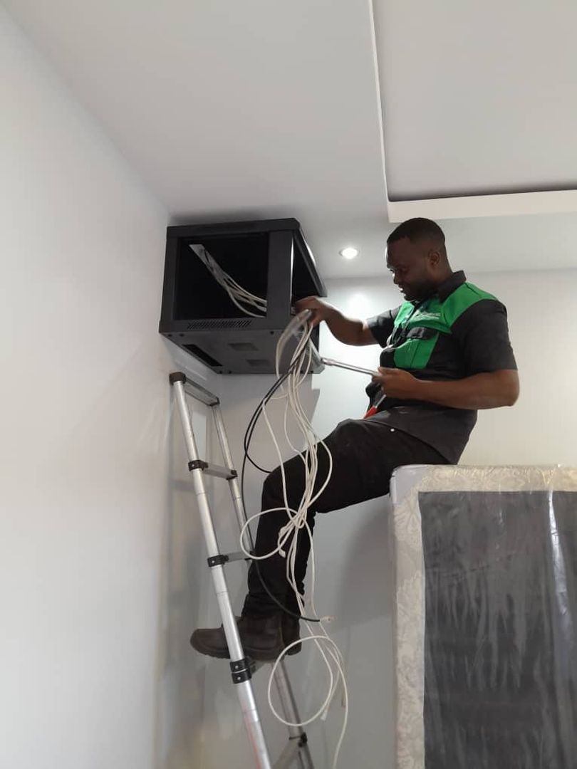 A technician running cable into a wall mounted equipment cabinet